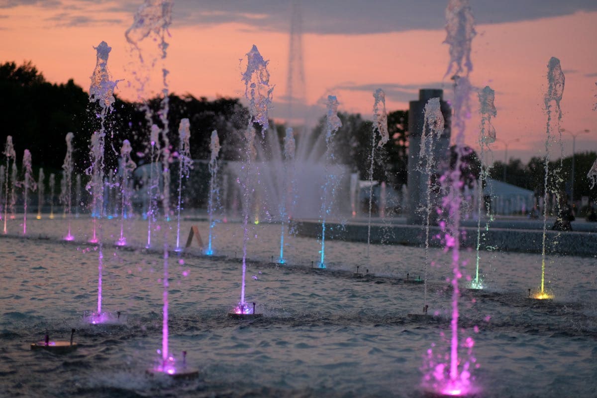 Colorful illuminated fountain at dusk with purple and blue water jets