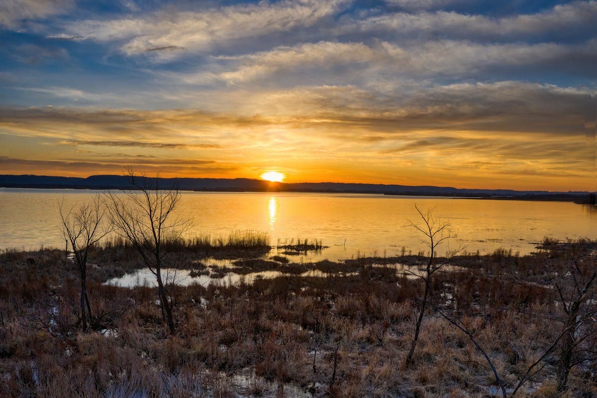 Golden sunset over marsh and water with dramatic clouds